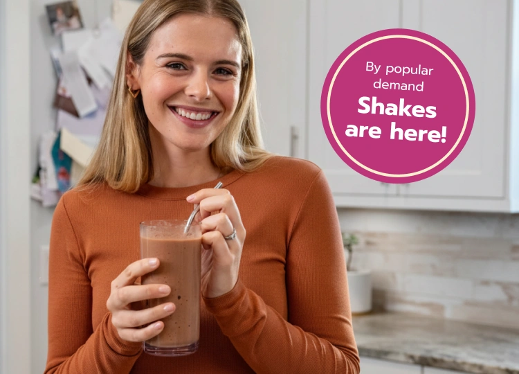 Woman smiling, holdng a chocolate shake - by popular demand, shakes are here!
